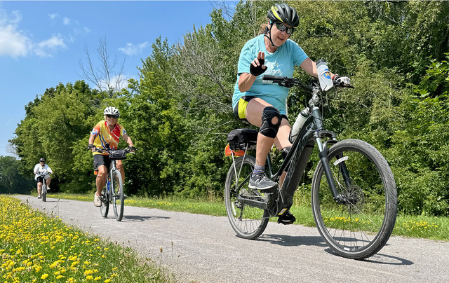 Three women are riding a bike on a bike path.