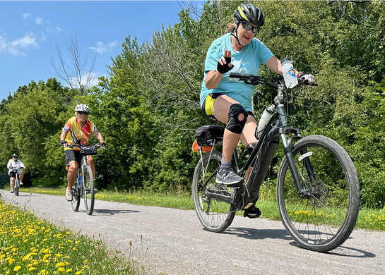 Three women are riding a bike on a bike path.