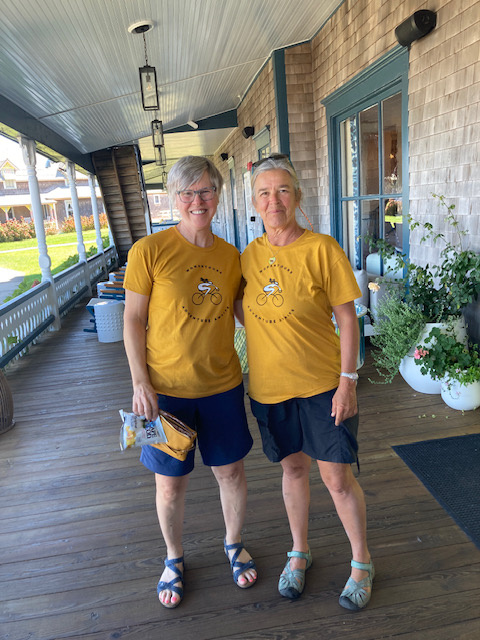 Two women pose for a photo on a front porch