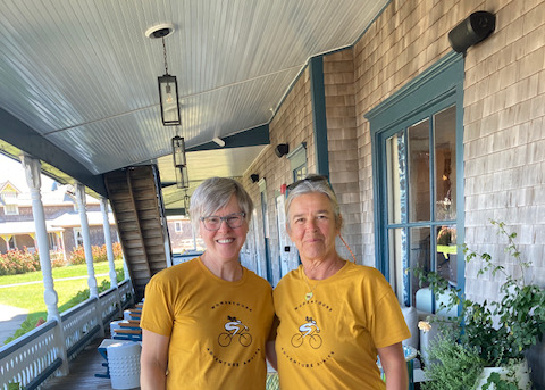 Two women pose for a photo on a front porch