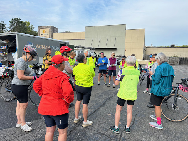 Women standing in a circle in front of a bike tour van.