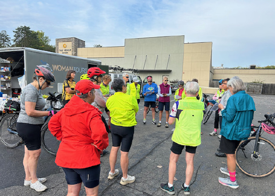 Women standing in a circle in front of a bike tour van.