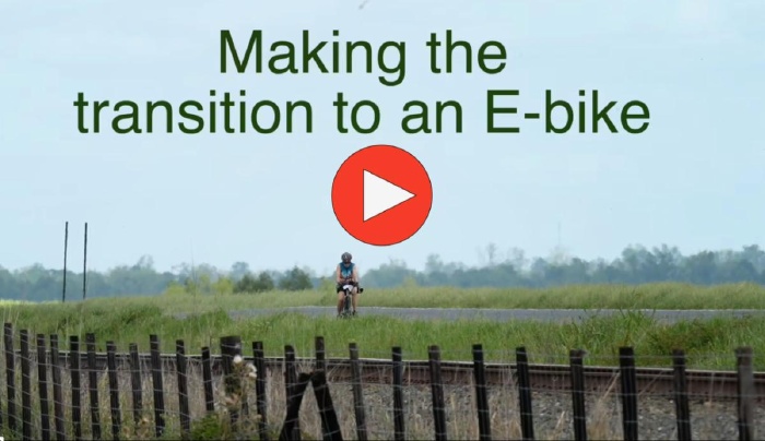 Photo shows a woman riding a bike on her own. It links to a video about how one woman transitioned from a regular road bike to an e-bike.