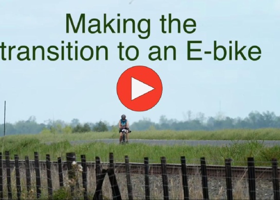 Photo shows a woman riding a bike on her own. It links to a video about how one woman transitioned from a regular road bike to an e-bike.